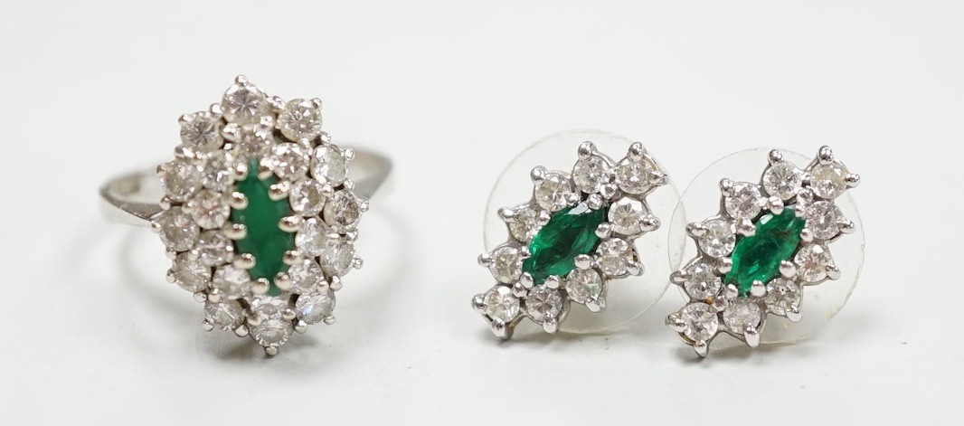 A modern 18ct white gold, emerald and diamond set oval cluster ring, size K/L and a pair of matching earrings, gross weight 7.2 grams.